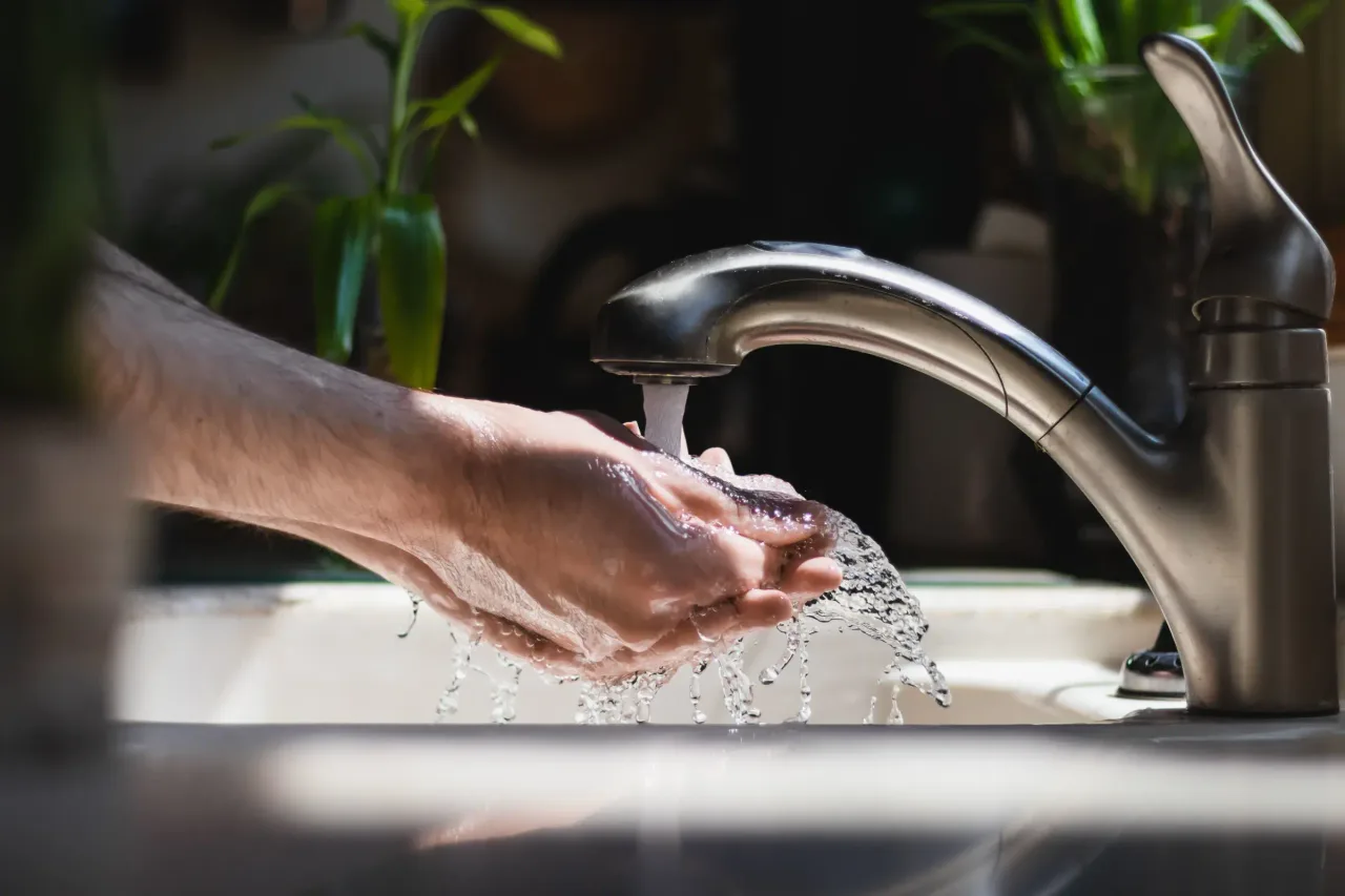 adult male washing hands under tap